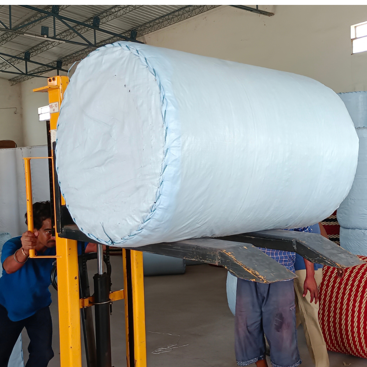 A forklift lifting a wrapped coir matting roll